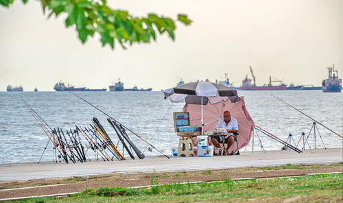 People on boats in sea against sky