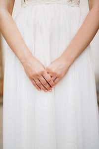 Midsection of woman holding umbrella standing against white wall