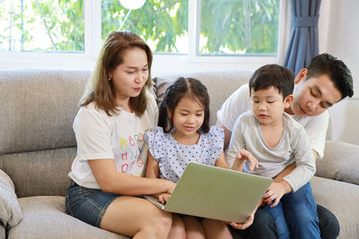 Happy friends sitting on sofa at home