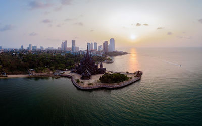 Panoramic view of sea and buildings against sky during sunset