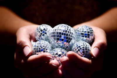 Close-up of woman holding shiny balls in darkroom