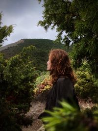 Rear view of woman looking at trees against sky