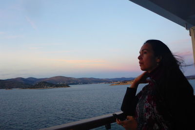 Side view of woman looking away against sky during sunset