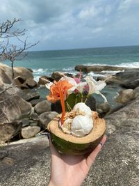 Hand holding flowers at beach