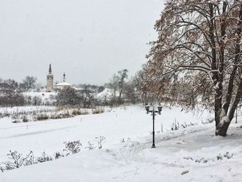 Snow covered field by building against sky