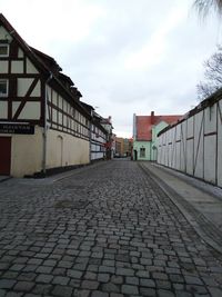 Cobblestone street in city against sky