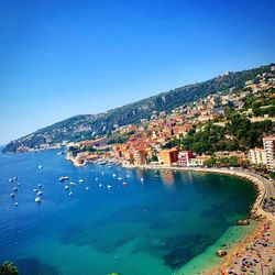 Scenic view of sea and townscape against clear blue sky