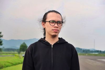 Portrait of man wearing eyeglasses standing against sky