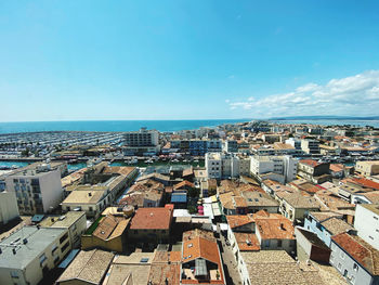 High angle view of townscape by sea against blue sky