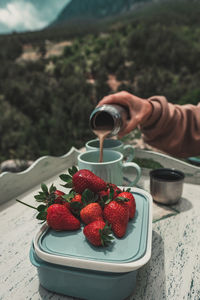 Delicious fresh strawberries and coffee. female hand pours coffee to cup from thermos.