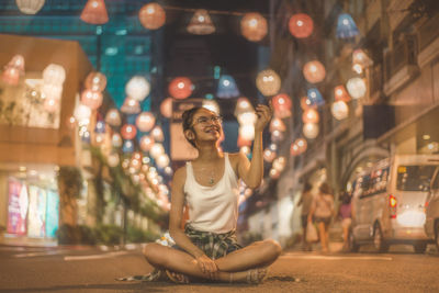 Full length of a smiling young woman sitting at night