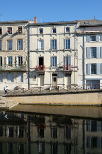 Reflection of building in canal against sky