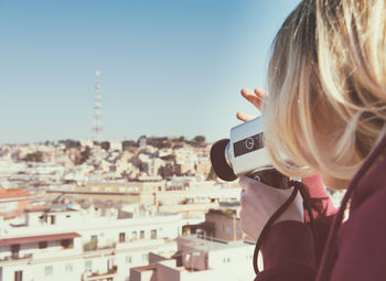 Rear view of woman photographing cityscape