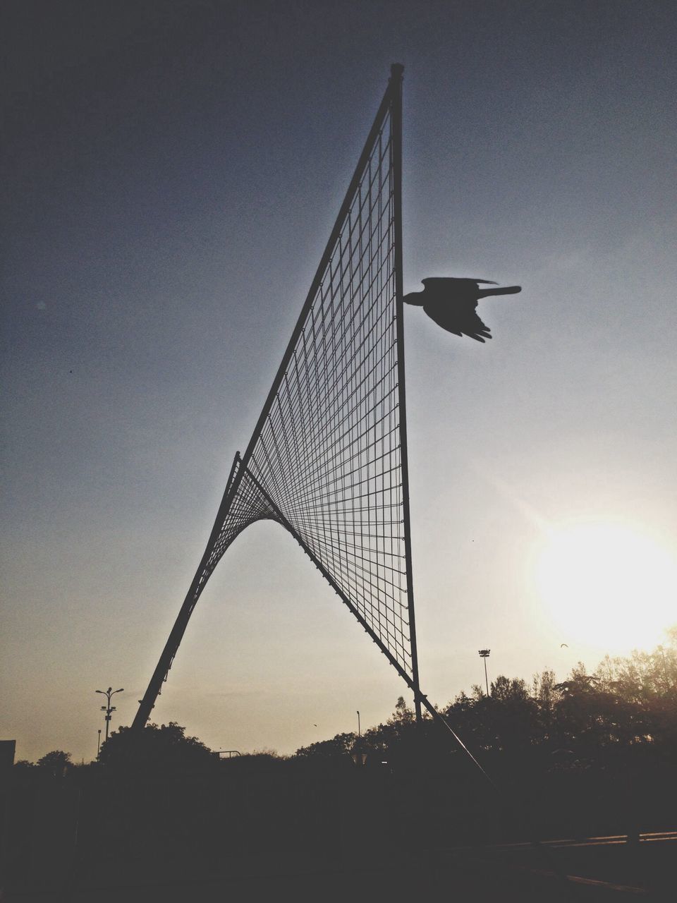 low angle view, built structure, silhouette, sunset, architecture, sky, connection, sun, clear sky, suspension bridge, bridge - man made structure, outdoors, sunlight, dusk, engineering, transportation, no people, copy space, development, travel destinations