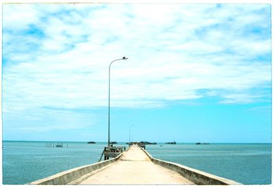 Pier on sea against cloudy sky