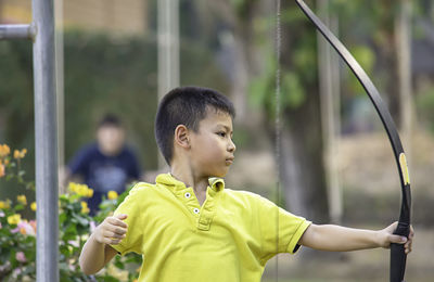 Cute boy practicing archery in park