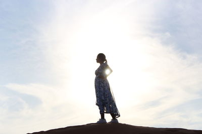 Side view of woman standing against sky