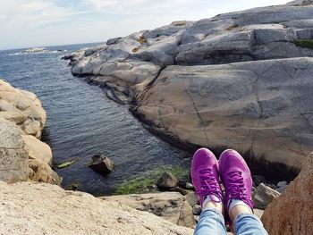 Low section of person on rock by sea