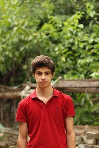 Portrait of young man standing against trees