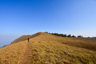 Hiker on mountain against clear blue sky