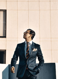 Portrait of businessman standing against wall