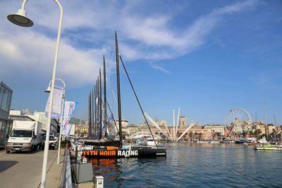 Sailboats moored at harbor against sky in city