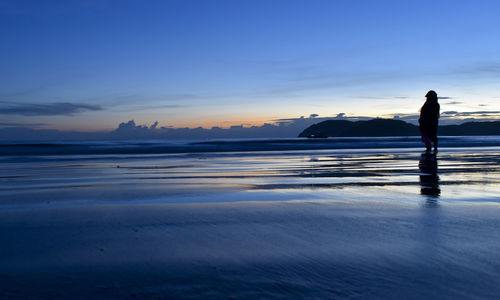 Silhouette man standing on beach against sky during sunset