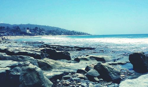 Scenic view of rocky beach against blue sky