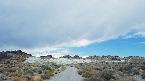 Scenic view of road by mountains against sky