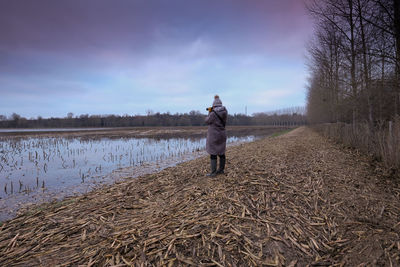 Rear view of man standing on field against sky