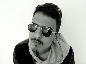 High angle portrait of young man wearing sunglasses against white background