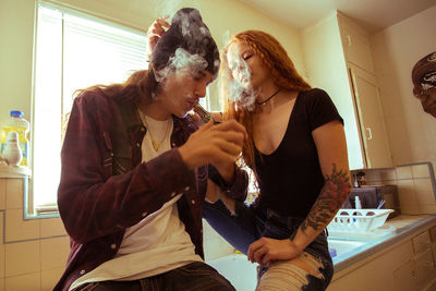 Young couple smoking in kitchen