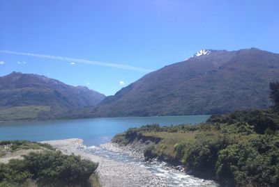 Scenic view of lake and mountains against blue sky