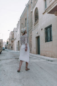 Full length of woman standing on street against building