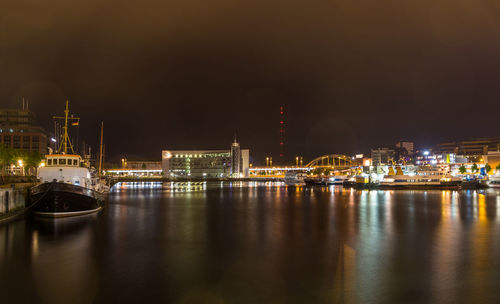 Illuminated city by sea against sky at night