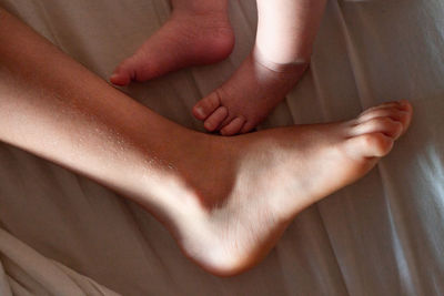 Close up view on feet of elder child and newborn baby on the bed