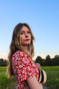 Portrait of beautiful woman on field against clear sky