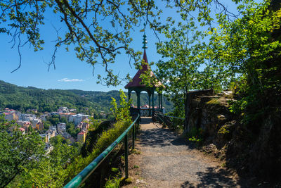 Footpath amidst trees and buildings against sky