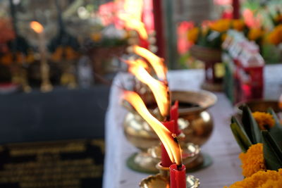 Close-up of lit candles on table in temple
