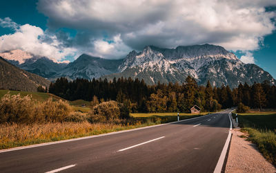 Panoramic view of road by snowcapped mountains against sky