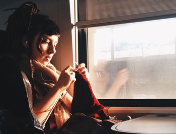 PORTRAIT OF YOUNG WOMAN SITTING ON WALL