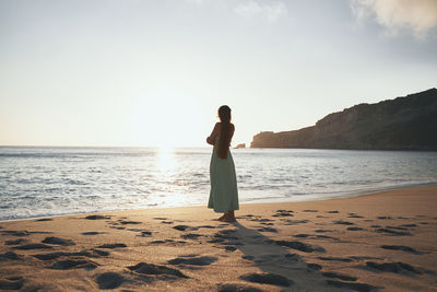 Woman standing at beach against sky