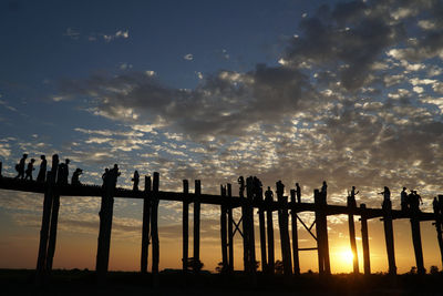 Silhouette fence on landscape against sky during sunset