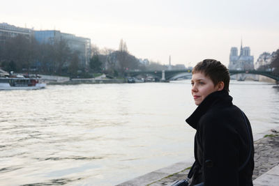 Young woman stands on the banks of  the seine and looks into the distance. paris, france.