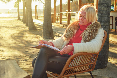 A middle-aged woman with blonde hair sits in a street cafe.