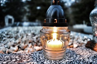 Close-up of lit tea light candles on pebbles