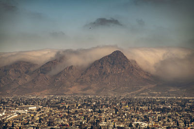 Aerial view of townscape and mountains against sky