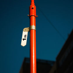 Low angle view of orange pole against clear blue sky