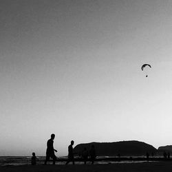 Silhouette people by sea against clear sky