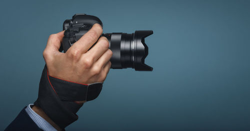 Close-up of hand holding camera against gray background